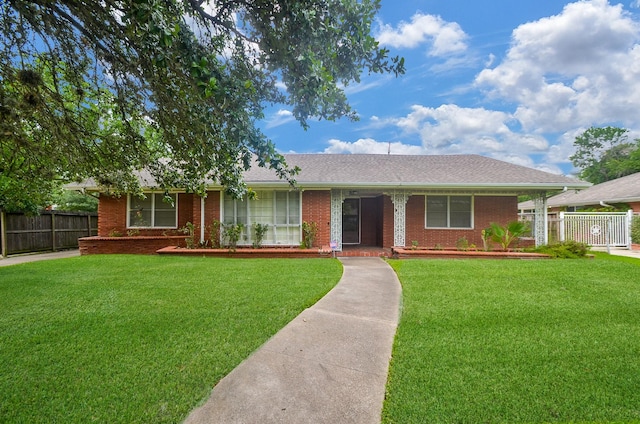 ranch-style house with brick siding, roof with shingles, a front yard, and fence