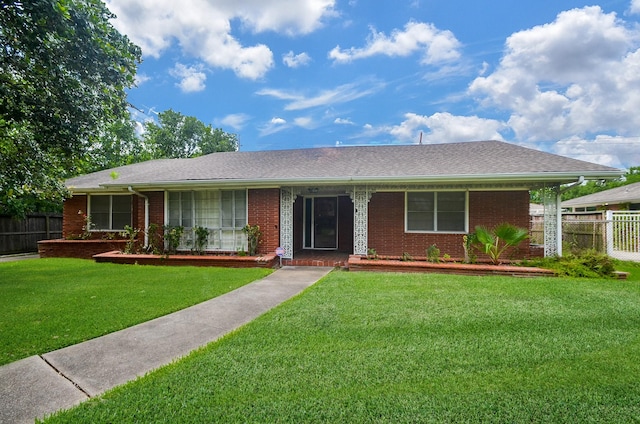 ranch-style home featuring a front lawn, fence, brick siding, and a shingled roof