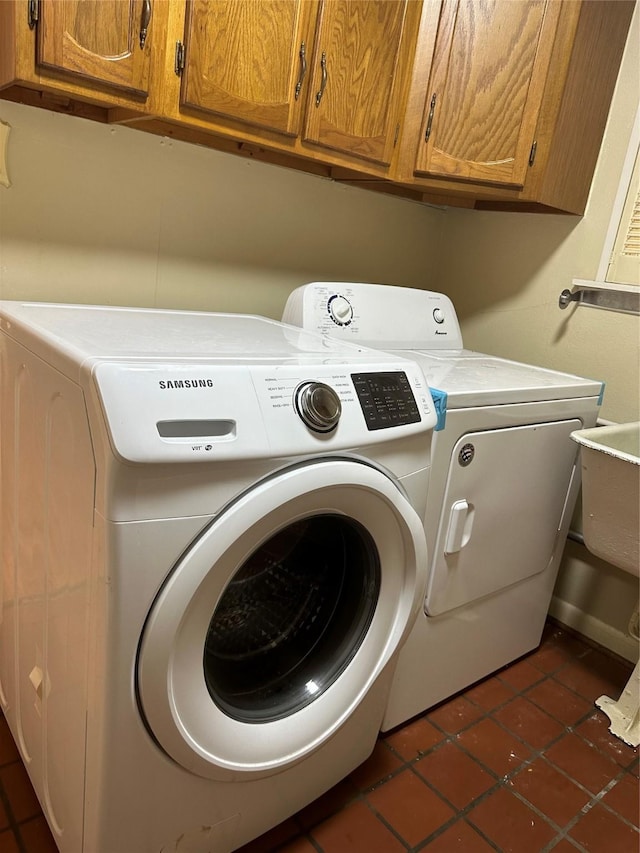 laundry area featuring cabinet space, dark tile patterned flooring, and washing machine and dryer