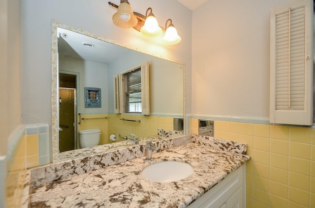 bathroom with a wainscoted wall, toilet, tile walls, and a stall shower