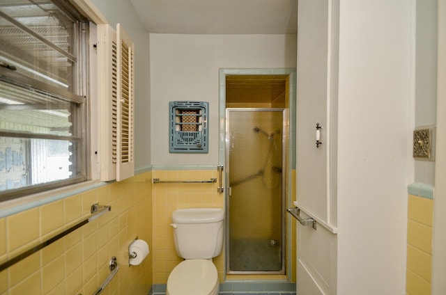 bathroom with a wainscoted wall, toilet, tile walls, and a stall shower