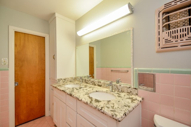 full bath with toilet, tile walls, and a sink