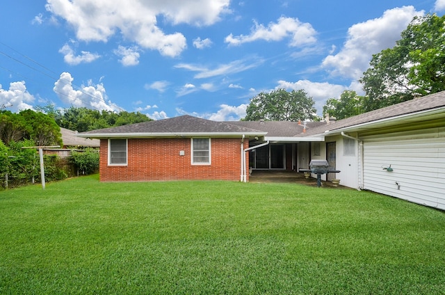 back of property with brick siding, a lawn, and roof with shingles