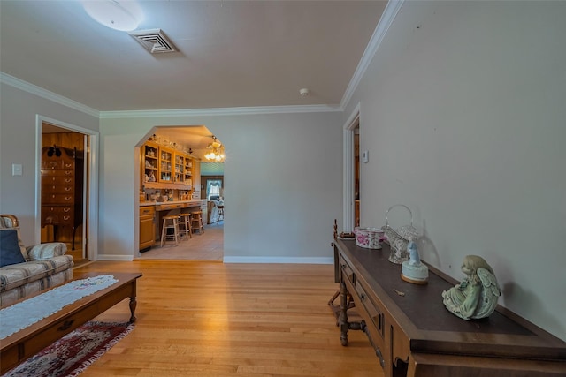 living room with light wood-type flooring, visible vents, arched walkways, and ornamental molding