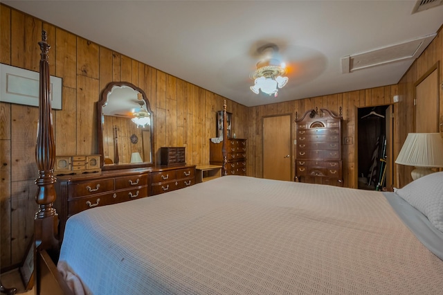 bedroom with attic access, a ceiling fan, visible vents, and wood walls