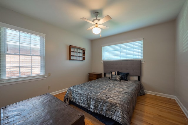 bedroom featuring baseboards, multiple windows, and wood finished floors