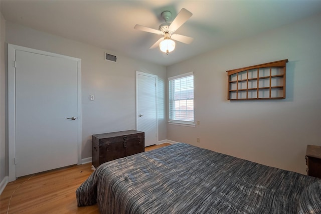 bedroom featuring baseboards, light wood-style floors, visible vents, and ceiling fan