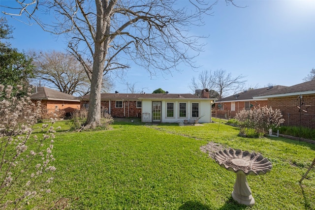 back of property with a yard, brick siding, and a chimney