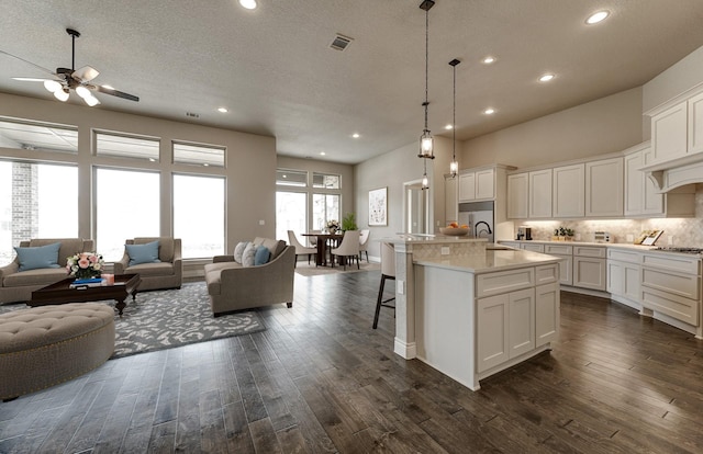 kitchen with dark wood-style floors, visible vents, a sink, decorative backsplash, and open floor plan