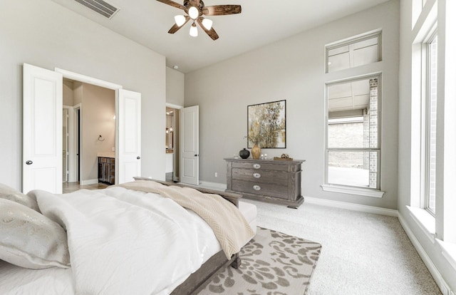 bedroom with baseboards, visible vents, ensuite bath, ceiling fan, and light carpet