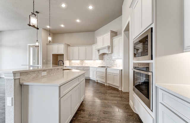 kitchen with dark wood finished floors, light countertops, appliances with stainless steel finishes, white cabinetry, and backsplash