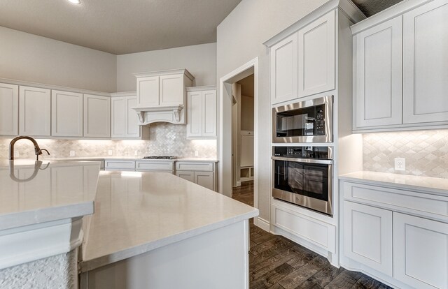 kitchen featuring decorative backsplash, dark wood-type flooring, appliances with stainless steel finishes, and light countertops