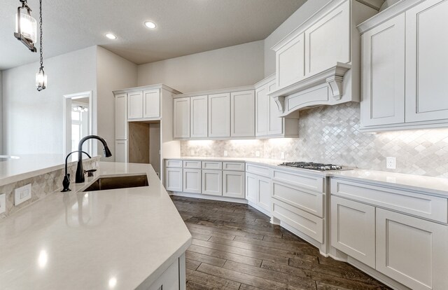 kitchen featuring light countertops, white cabinets, stainless steel gas cooktop, and a sink