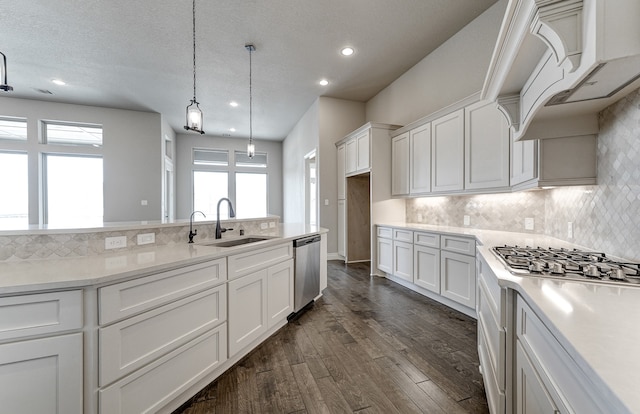 kitchen with a sink, dark wood-style floors, appliances with stainless steel finishes, white cabinets, and light countertops