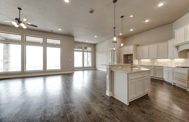 kitchen with tasteful backsplash, visible vents, open floor plan, dark wood-style floors, and a sink