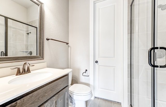 bathroom featuring a shower stall, vanity, toilet, and a textured wall