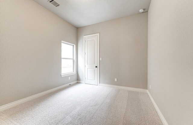 spare room featuring carpet flooring, baseboards, and visible vents