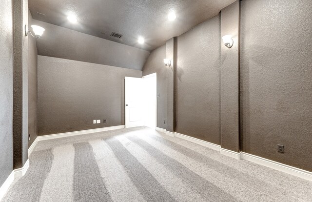 carpeted spare room featuring visible vents, baseboards, lofted ceiling, a textured ceiling, and a textured wall