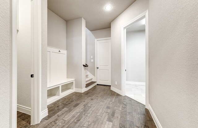 mudroom with baseboards, wood finished floors, and a textured wall