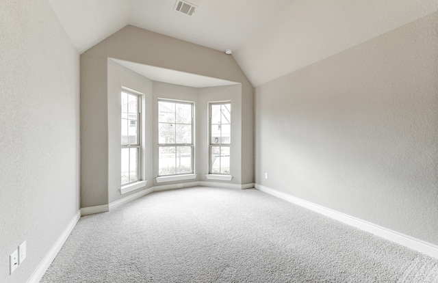 empty room with visible vents, lofted ceiling, baseboards, and carpet flooring