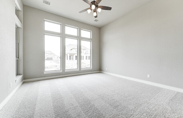 carpeted empty room with baseboards, visible vents, and ceiling fan