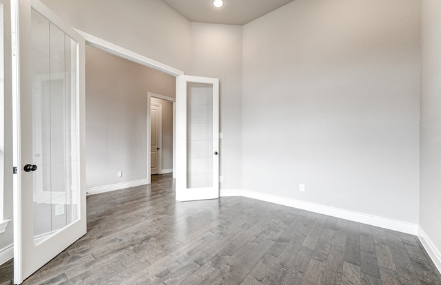 spare room with dark wood finished floors, french doors, and baseboards