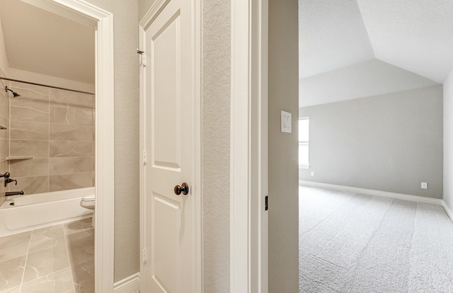 bathroom with baseboards, lofted ceiling, toilet, and washtub / shower combination