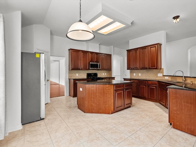 kitchen featuring a sink, tasteful backsplash, a center island, stainless steel appliances, and arched walkways