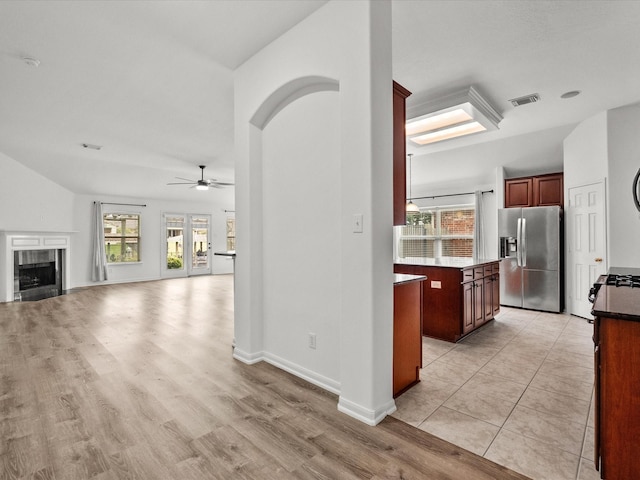 kitchen with visible vents, light wood-style flooring, a ceiling fan, a fireplace, and stainless steel fridge with ice dispenser