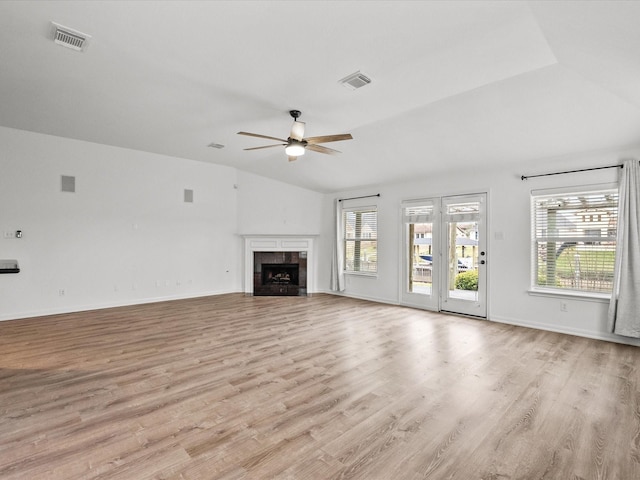 unfurnished living room featuring visible vents, light wood-style flooring, a tile fireplace, and vaulted ceiling