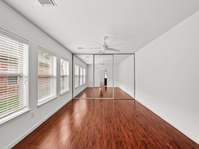 interior space with ceiling fan, visible vents, baseboards, and wood finished floors