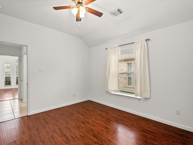 unfurnished room with a wealth of natural light, visible vents, wood finished floors, and vaulted ceiling