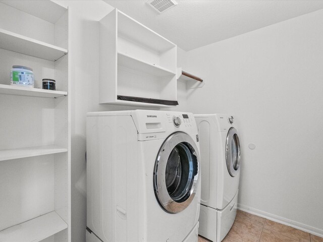 clothes washing area with visible vents, baseboards, light tile patterned floors, laundry area, and washer and dryer