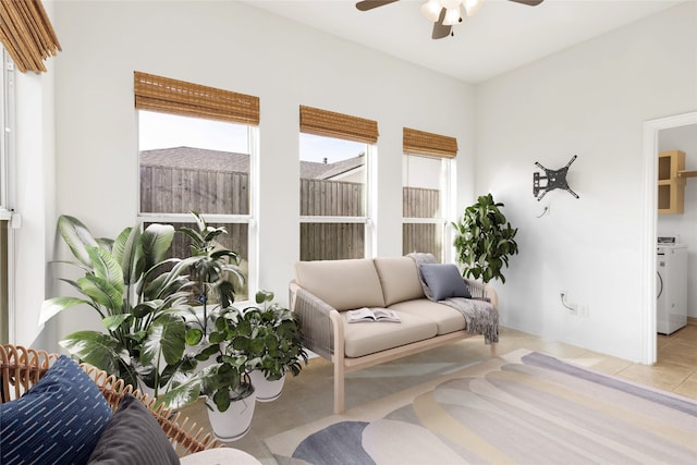 sitting room featuring a ceiling fan, washer / dryer, a healthy amount of sunlight, and tile patterned floors