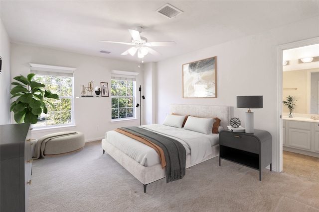 bedroom with visible vents, light carpet, ensuite bath, and a ceiling fan