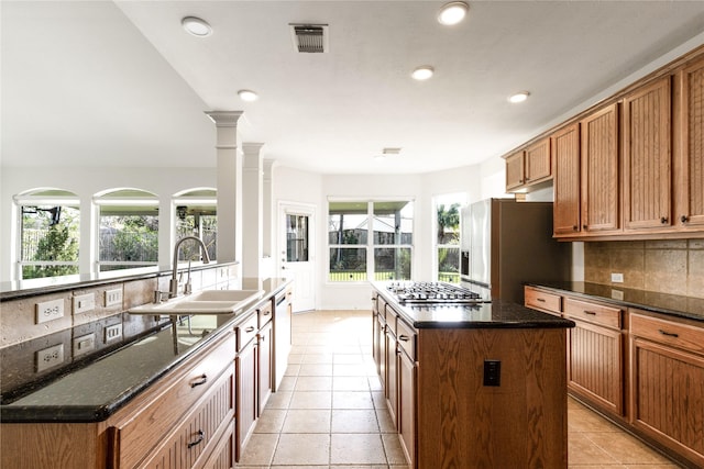 kitchen featuring tasteful backsplash, visible vents, a kitchen island, appliances with stainless steel finishes, and a sink