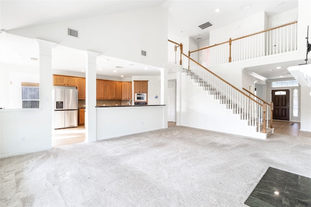 unfurnished living room featuring decorative columns, light carpet, visible vents, and stairs