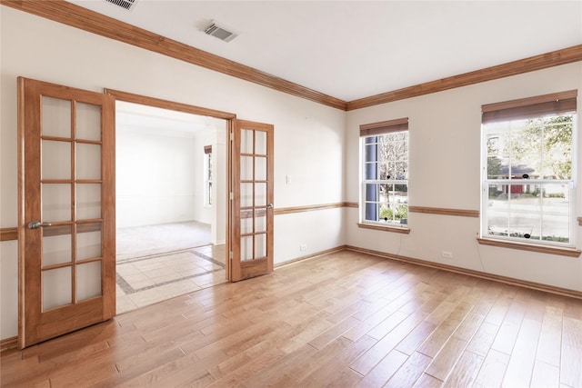 unfurnished room with visible vents, light wood-style flooring, a healthy amount of sunlight, and ornamental molding