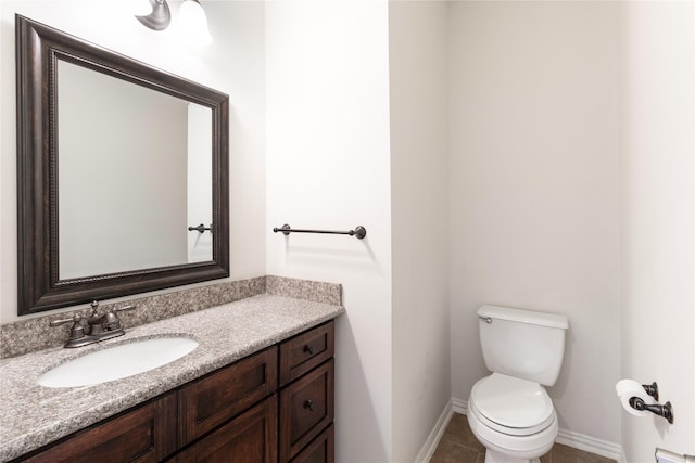 half bathroom with vanity, tile patterned floors, toilet, and baseboards