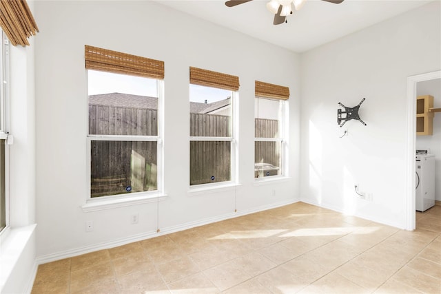 tiled spare room with baseboards, washer / dryer, and a ceiling fan