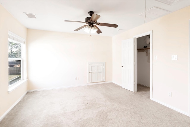 empty room with visible vents, baseboards, light colored carpet, attic access, and ceiling fan