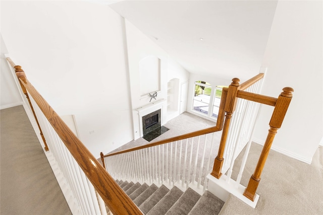 stairs with baseboards, a fireplace with flush hearth, high vaulted ceiling, and carpet flooring