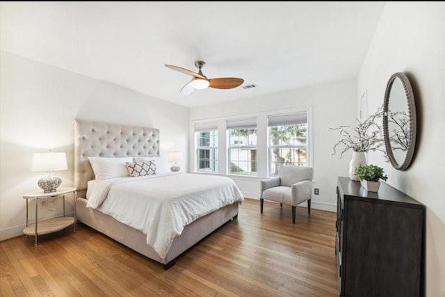 bedroom with ceiling fan, light wood-style floors, visible vents, and baseboards