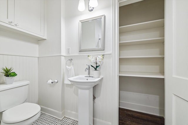 bathroom featuring a sink, a wainscoted wall, and toilet