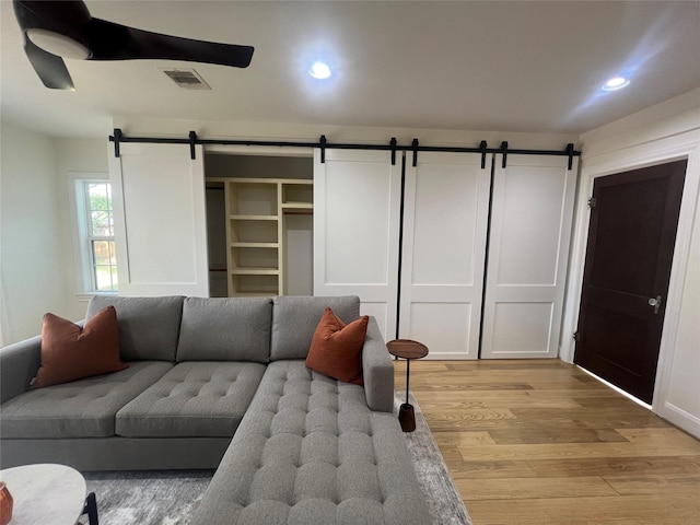 living area featuring light wood finished floors, visible vents, recessed lighting, and a barn door