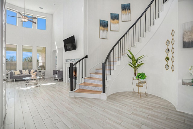 entrance foyer with stairs, plenty of natural light, wood finished floors, and a warm lit fireplace