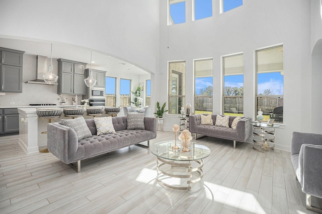 living room with arched walkways, a healthy amount of sunlight, and light wood-style floors