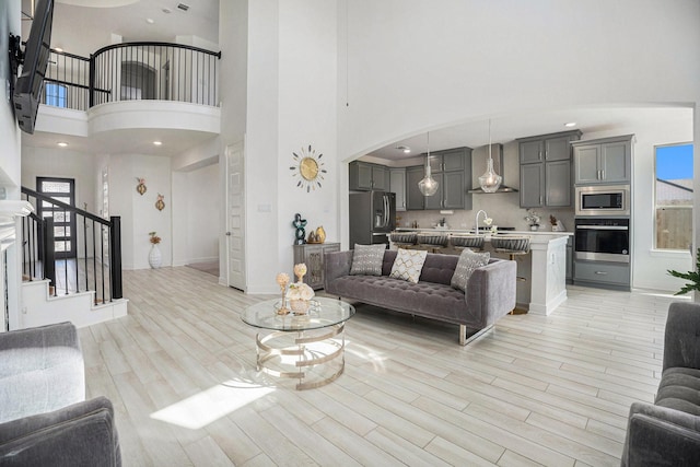 living room featuring a wealth of natural light, stairway, arched walkways, and light wood finished floors