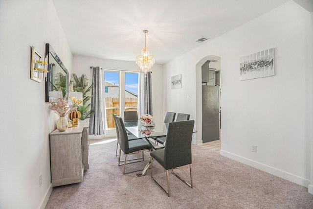 dining room featuring visible vents, baseboards, an inviting chandelier, arched walkways, and light colored carpet