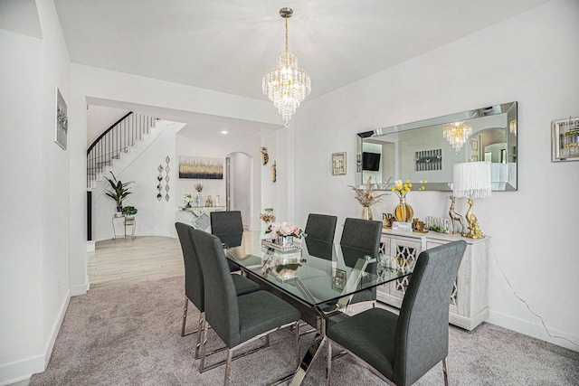 dining area featuring a notable chandelier, carpet floors, arched walkways, baseboards, and stairs